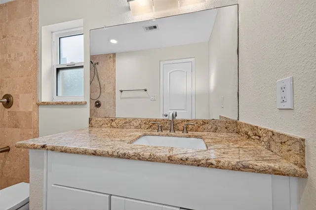 a bathroom with a granite countertop sink and a mirror