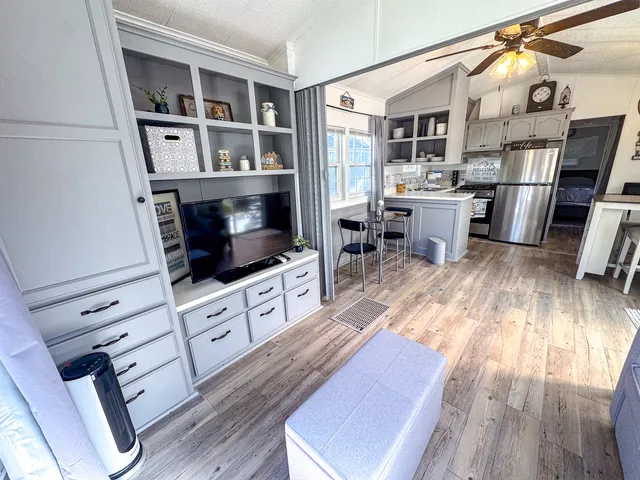 a living room with stainless steel appliances furniture and a wooden floor