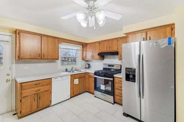 a kitchen with stainless steel appliances granite countertop a refrigerator a sink dishwasher a stove with wooden cabinets and floor