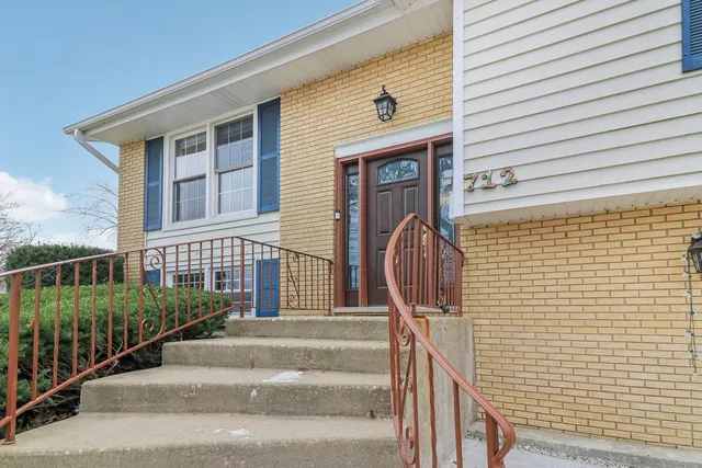 a view of a brick house with large windows and stairs