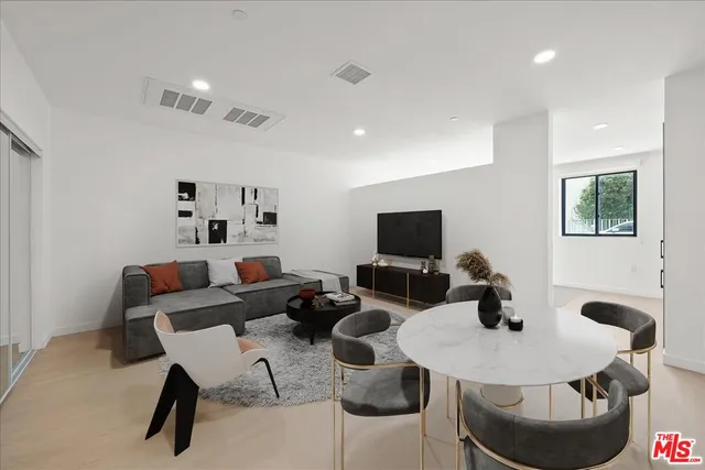 a living room with furniture a flat screen tv and kitchen view