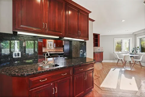 a kitchen with granite countertop a stove a sink dishwasher and cabinets with wooden floor