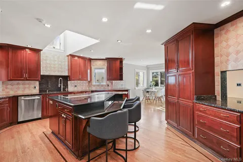 a kitchen with kitchen island granite countertop wooden cabinets and stainless steel appliances