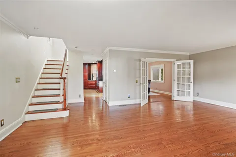a view of an empty room with wooden floor and stairs