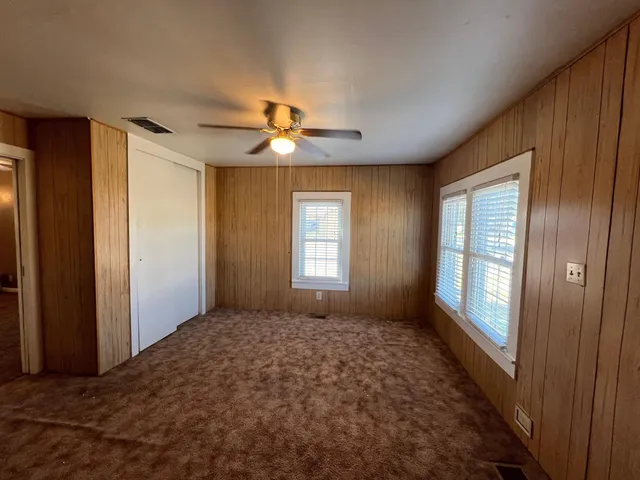 a big room with windows and a chandelier fan
