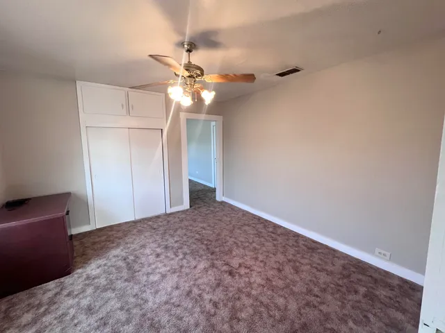 an empty room with a chandelier fan and closet