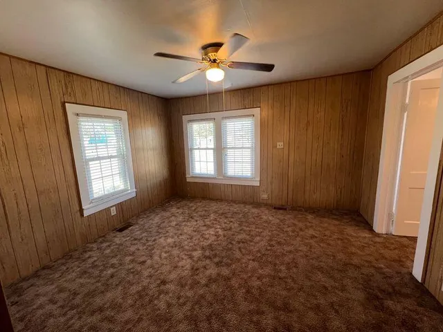a view of an empty room with window and chandelier fan