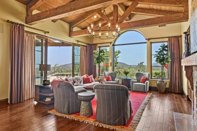 a living room with furniture a large window and wooden floor