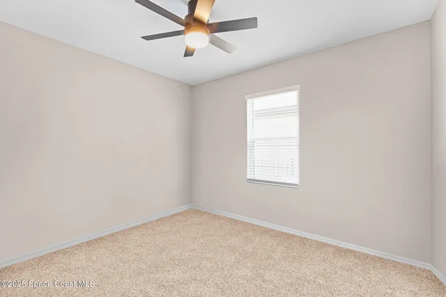 an empty room with a window and a fan