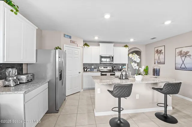 a kitchen with refrigerator and chairs