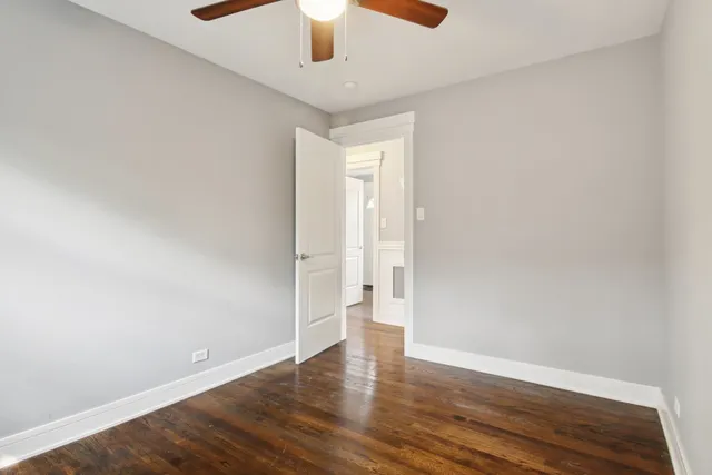 an empty room with wooden floor and ceiling fan