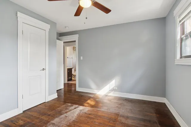 an empty room with wooden floor cabinet and windows