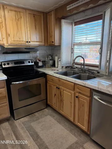 a kitchen with granite countertop a stove a sink and a white cabinets