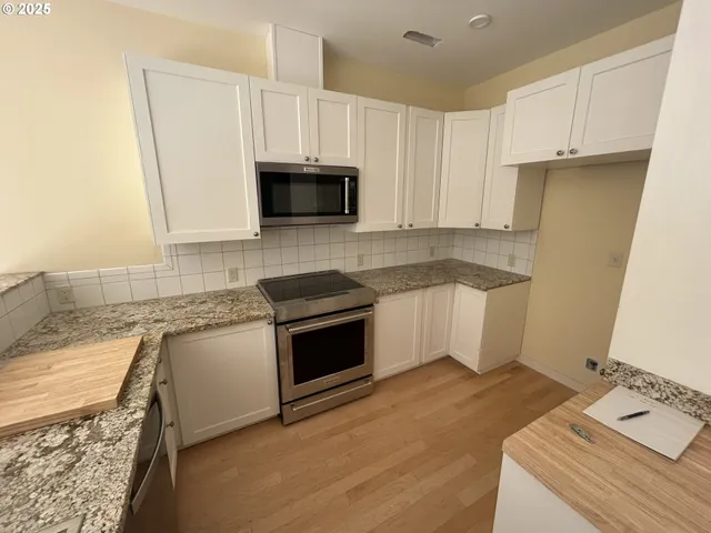 a kitchen with granite countertop a sink a stove and cabinets