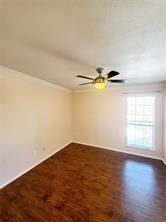 18333 Roehampton Drive, Unit 825 Dallas, TX 75252 - Photo 3 of 7 Spacious room featuring wood-finish flooring, a ceiling fan with integrated lighting, crown molding, and a window providing natural light