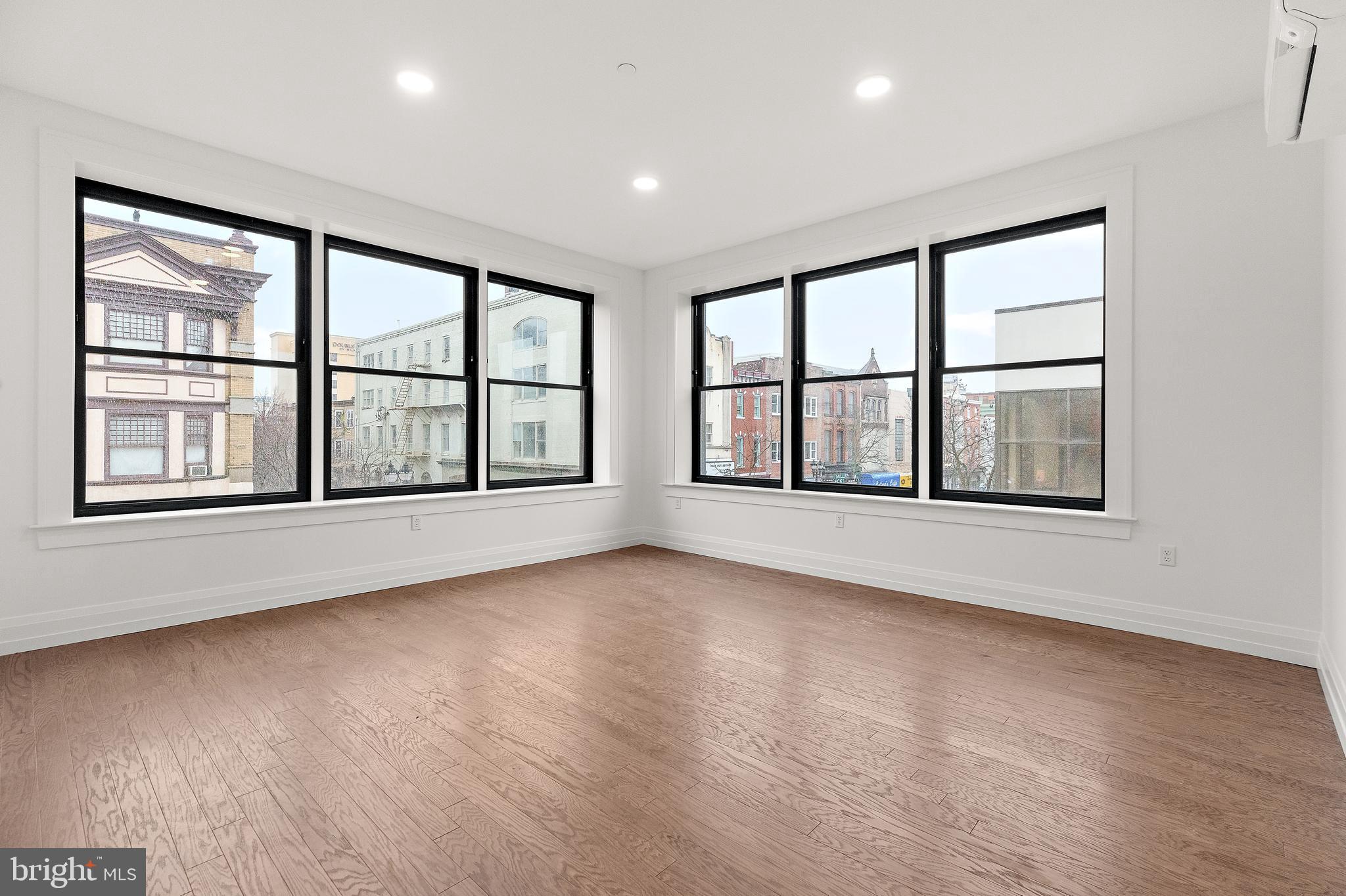 a view of an empty room with a window and hardwood floor