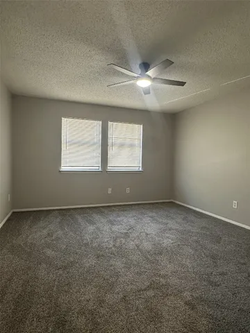 an empty room with a window and a fan