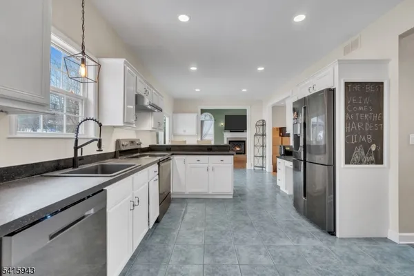 a open kitchen with stainless steel appliances granite countertop a refrigerator a sink a stove and oven with wooden floor