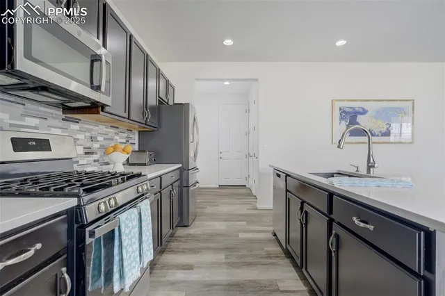 a kitchen with stainless steel appliances granite countertop a stove a sink and a refrigerator