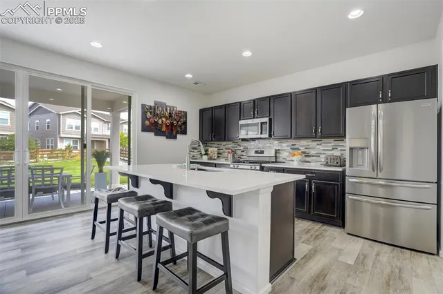 a kitchen with stainless steel appliances a stove a sink a refrigerator a dining table and chairs