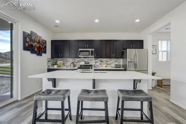 a kitchen with stainless steel appliances a table chairs refrigerator and microwave