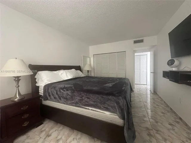 a bedroom with a bed and a flat tv screen on a dresser