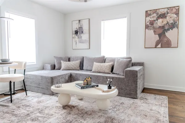 a living room with furniture a table and a painting next to a window