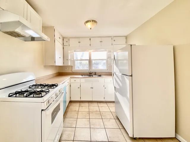 a kitchen with a stove a refrigerator and a white cabinets