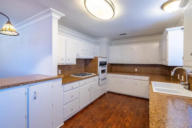 a kitchen with granite countertop white cabinets and white appliances