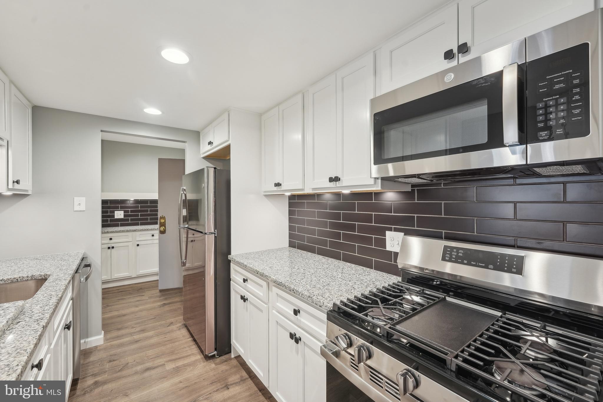 203 Drummers Lane, Unit 203 Wayne, PA 19087 - Photo 10 of 40 a kitchen with stainless steel appliances kitchen island granite countertop a stove and a microwave