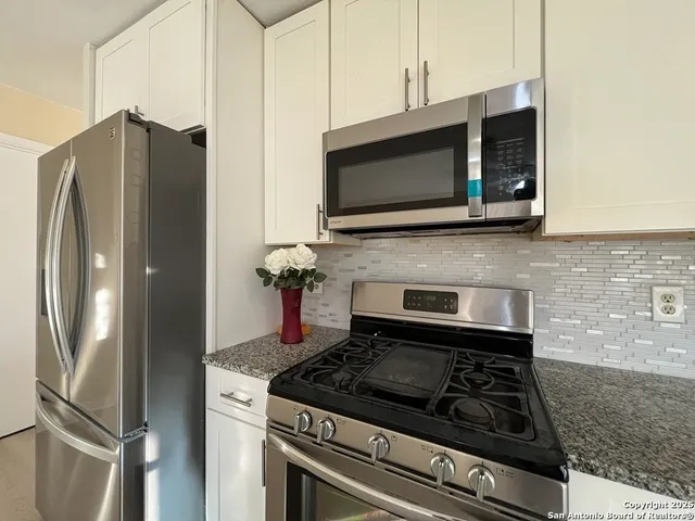 a kitchen with stainless steel appliances granite countertop a stove and a microwave