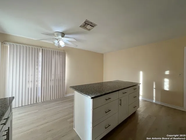 a kitchen with granite countertop white cabinets and window