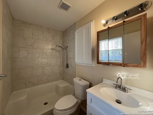a bathroom with a bathtub shower sink vanity and toilet