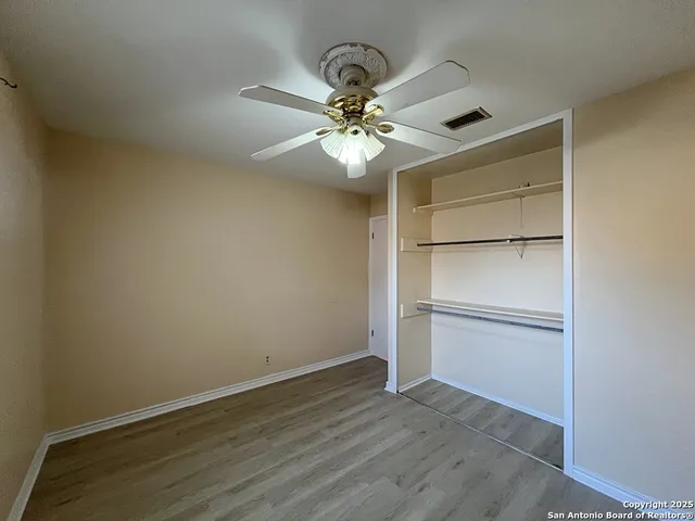 a view of an empty room with a ceiling fan and wooden floor