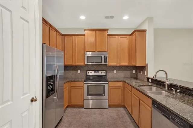 a kitchen with stainless steel appliances granite countertop a stove sink and refrigerator