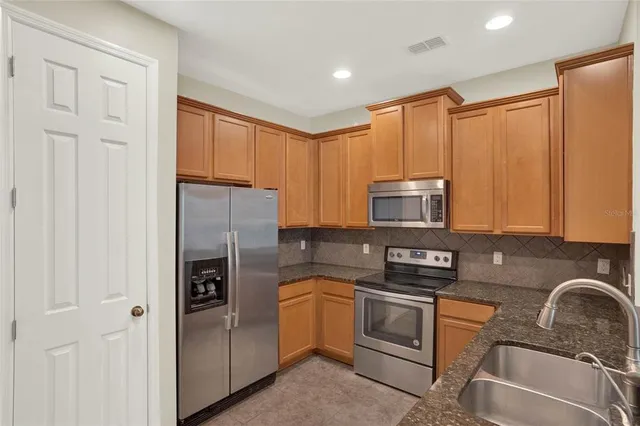 a kitchen with stainless steel appliances granite countertop a refrigerator stove and sink