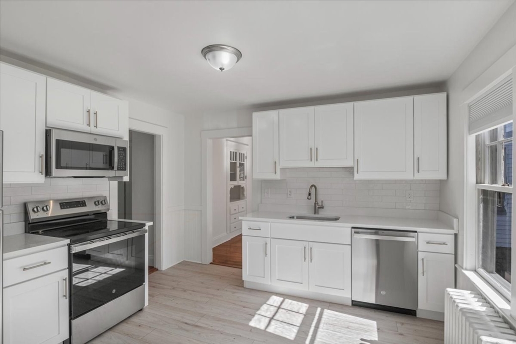 a kitchen with white cabinets stainless steel appliances and sink