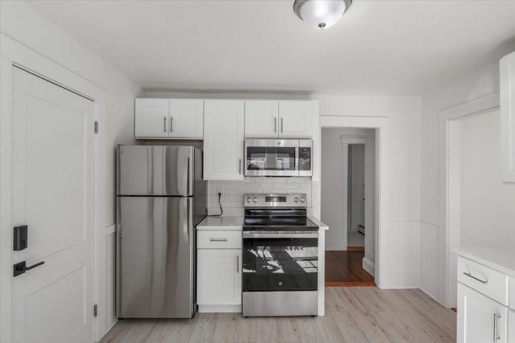 558 Lagrange Street, Unit 1 Boston, MA 02132 - Photo 12 of 40 a kitchen with stainless steel appliances a refrigerator and a stove top oven