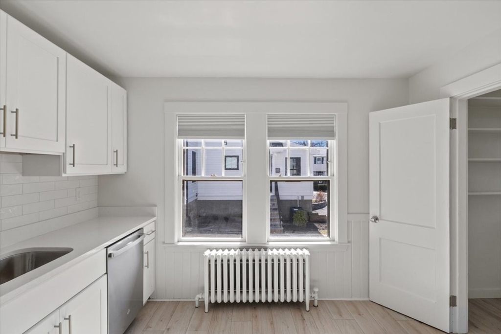 558 Lagrange Street, Unit 1 Boston, MA 02132 - Photo 13 of 40 a kitchen with white cabinets and a sink