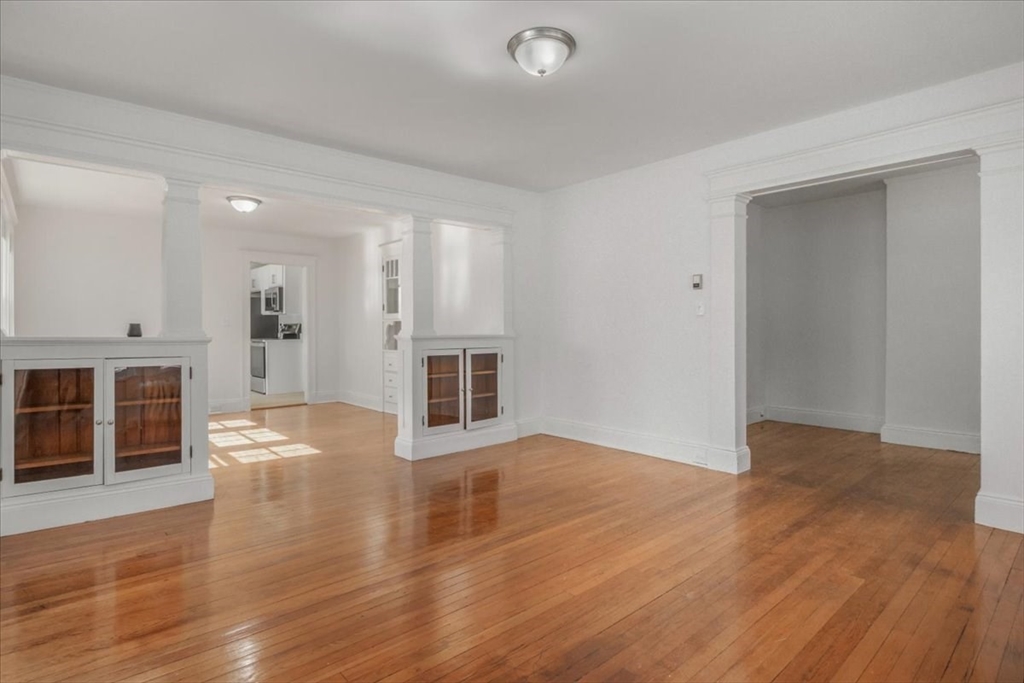 558 Lagrange Street, Unit 1 Boston, MA 02132 - Photo 19 of 40 a view of an empty room with wooden floor and a fireplace