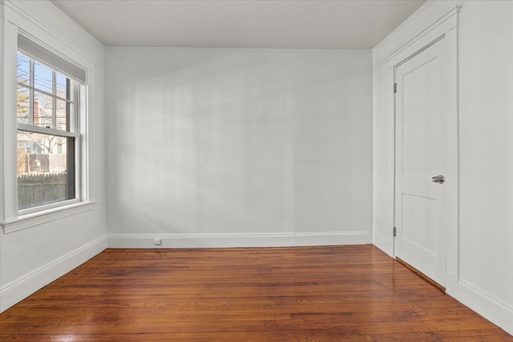 558 Lagrange Street, Unit 1 Boston, MA 02132 - Photo 27 of 40 a view of an empty room with wooden floor and a window
