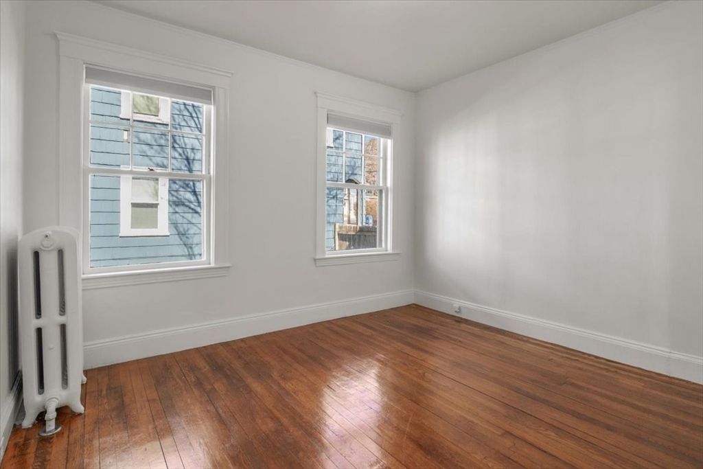 558 Lagrange Street, Unit 1 Boston, MA 02132 - Photo 29 of 40 a view of an empty room with wooden floor and a window