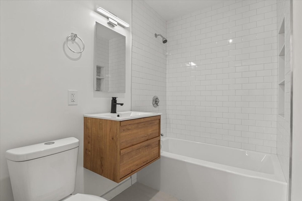 558 Lagrange Street, Unit 1 Boston, MA 02132 - Photo 5 of 40 a bathroom with a sink a toilet and a mirror