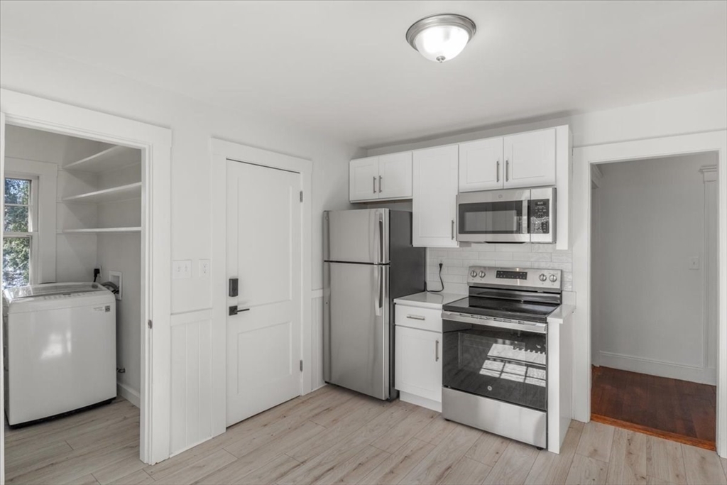558 Lagrange Street, Unit 1 Boston, MA 02132 - Photo 9 of 40 a kitchen with white cabinets and stainless steel appliances