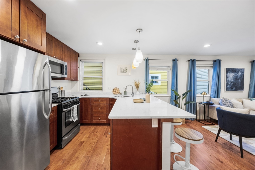 50 Spring Street Cambridge, MA 02141 - Photo 6 of 36 a kitchen with stainless steel appliances granite countertop a refrigerator a sink dishwasher a stove and a dining table with wooden floor