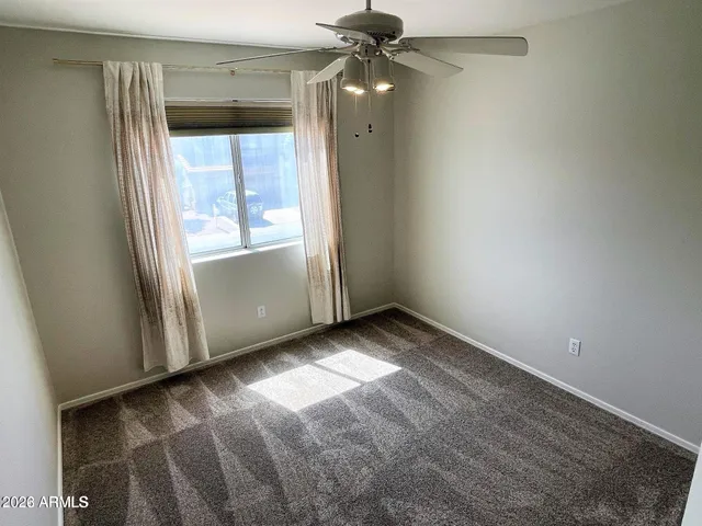 an empty room with windows and fan