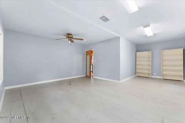 an empty room with ceiling fan and window