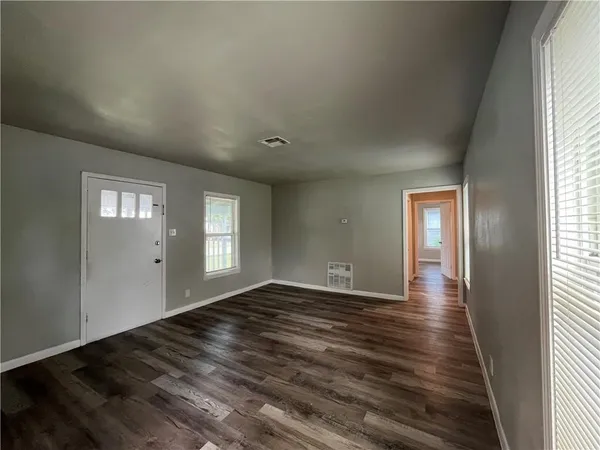 a view of an empty room with window and wooden floor