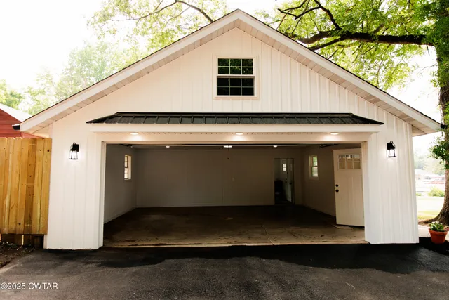 an empty room with a window and chandelier fan