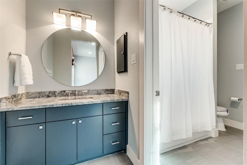 7912 Hanover Street Dallas, TX 75225 - Photo 15 of 29 Contemporary bathroom vanity featuring a circular mirror, modern light fixture, polished countertop, and ample storage cabinetry